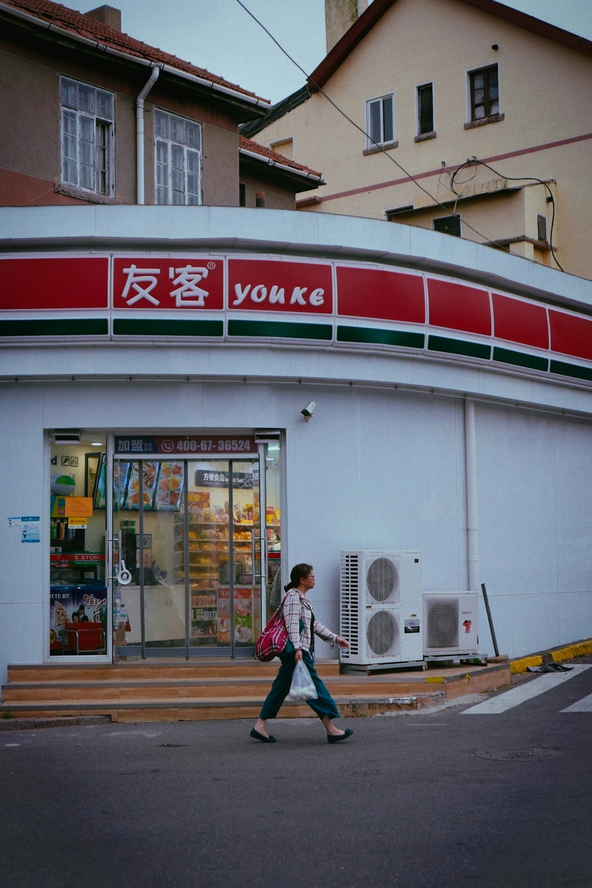 a woman walking down a street past a store
